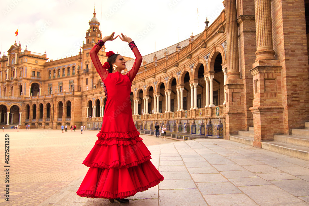 Beautiful teenage woman dancing flamenco in a square in Seville, Spain. She wears a red dress with ruffles and dances flamenco with a lot of art. Flamenco cultural heritage of humanity. - obrazy, fototapety, plakaty 