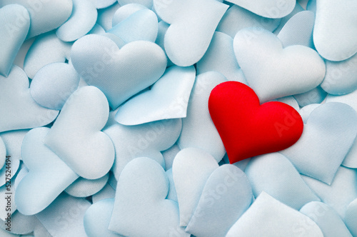 One single red textile heart on multiple pastel blue hearts with copy space concept for bond between lovers, romantic relationship and romance backgrounds