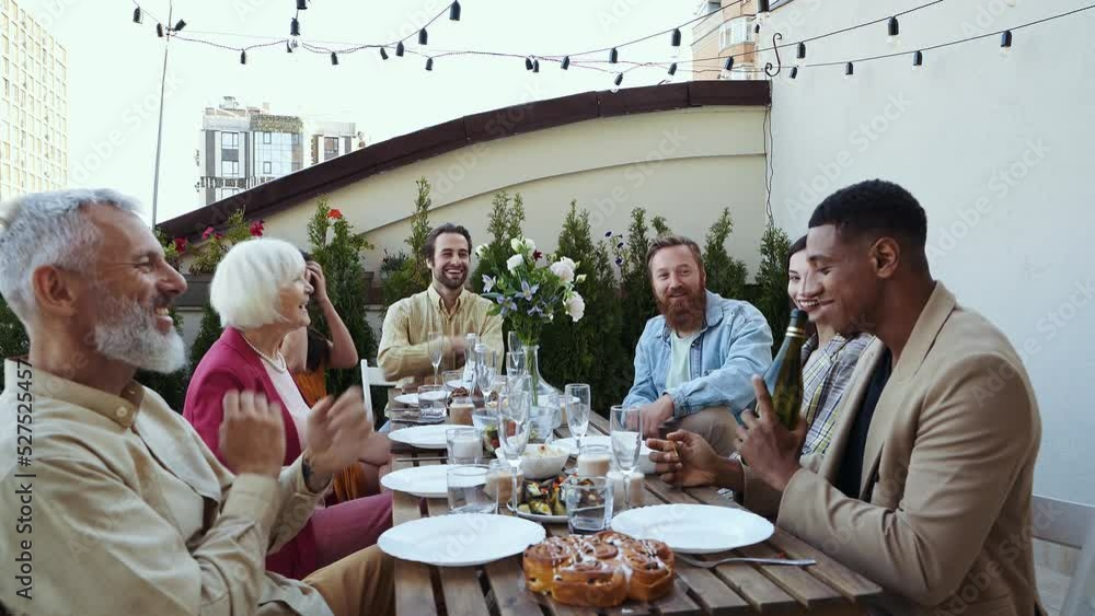 Family and friends celebrating at dinner on a rooftop terrace. Multiethnic group of people dining on the balcony on a special evening to celebrate friendship and family love and relationships Family and friends celebrating at dinner on a rooftop terrace. Multiethnic group of people dining on the balcony on a special evening to celebrate friendship and family love and relationships