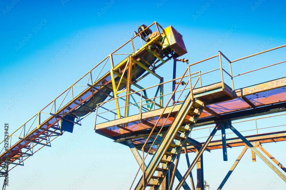 Old metal conveyor belt in an abandoned factory against a blue background Old metal conveyor belt in an abandoned factory against a blue background