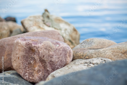 Wallpaper with stones by the river and water. Take a walk in the park on a summer day and admire the beautiful scenery. Selective focus, wallpaper.