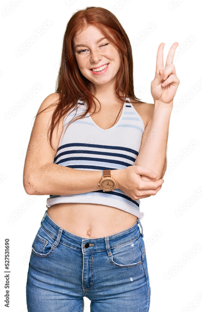Young read head woman wearing casual clothes smiling with happy face winking at the camera doing victory sign. number two. Young read head woman wearing casual clothes smiling with happy face winking at the camera doing victory sign. number two.