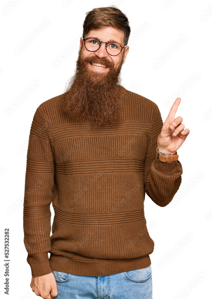 Young irish redhead man wearing casual clothes and glasses with a big smile on face, pointing with hand finger to the side looking at the camera. Young irish redhead man wearing casual clothes and glasses with a big smile on face, pointing with hand finger to the side looking at the camera.