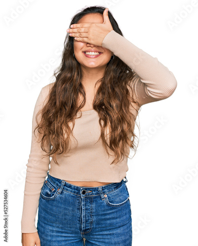 Young hispanic girl wearing casual clothes smiling and laughing with hand on face covering eyes for surprise. blind concept.