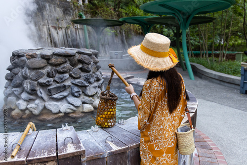 Travel woman put a basket into hot spring for cooking in Jioujhihze of Taipingshan in Taiwan photo