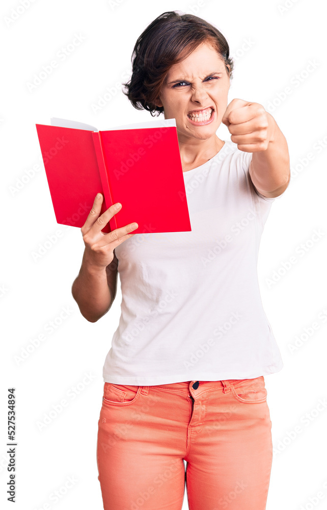 Beautiful young woman with short hair reading a book annoyed and frustrated shouting with anger, yelling crazy with anger and hand raised Beautiful young woman with short hair reading a book annoyed and frustrated shouting with anger, yelling crazy with anger and hand raised