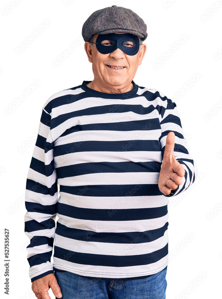 Senior handsome man wearing burglar mask and t-shirt smiling cheerful offering palm hand giving assistance and acceptance. Senior handsome man wearing burglar mask and t-shirt smiling cheerful offering palm hand giving assistance and acceptance.