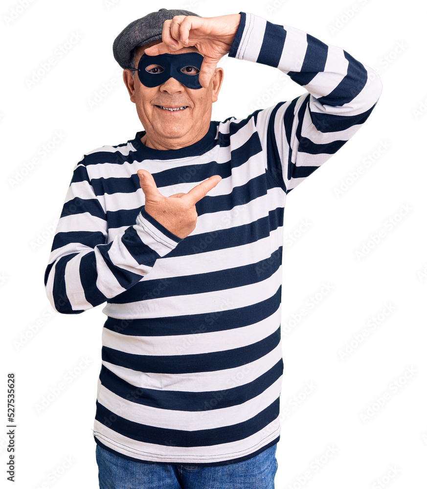 Senior handsome man wearing burglar mask and t-shirt smiling making frame with hands and fingers with happy face. creativity and photography concept. Senior handsome man wearing burglar mask and t-shirt smiling making frame with hands and fingers with happy face. creativity and photography concept.