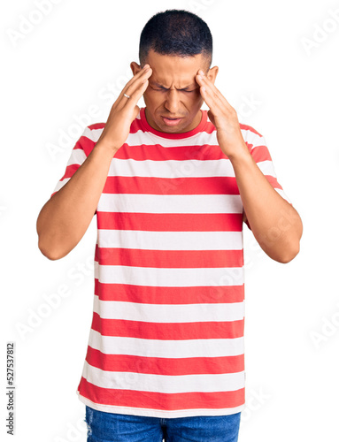 Young handsome latin man wearing casual clothes with hand on head for pain in head because stress. suffering migraine.