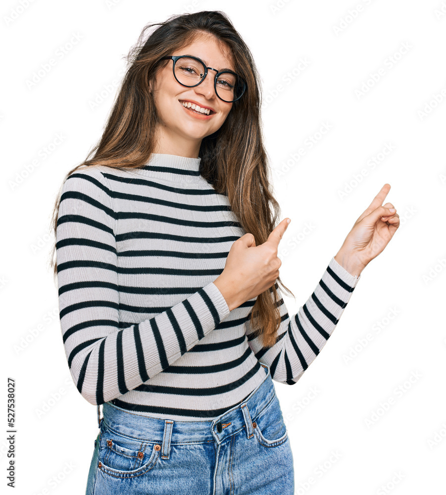 Young beautiful teen girl wearing casual clothes and glasses smiling and looking at the camera pointing with two hands and fingers to the side. Young beautiful teen girl wearing casual clothes and glasses smiling and looking at the camera pointing with two hands and fingers to the side.