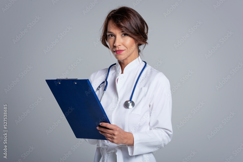 Smiling female doctor looking at camera and smiling while standing against at isolated background Smiling female doctor looking at camera and smiling while standing against at isolated background