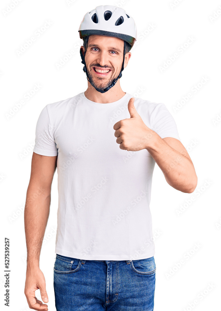 Young handsome man wearing bike helmet doing happy thumbs up gesture with hand. approving expression looking at the camera showing success. Young handsome man wearing bike helmet doing happy thumbs up gesture with hand. approving expression looking at the camera showing success.