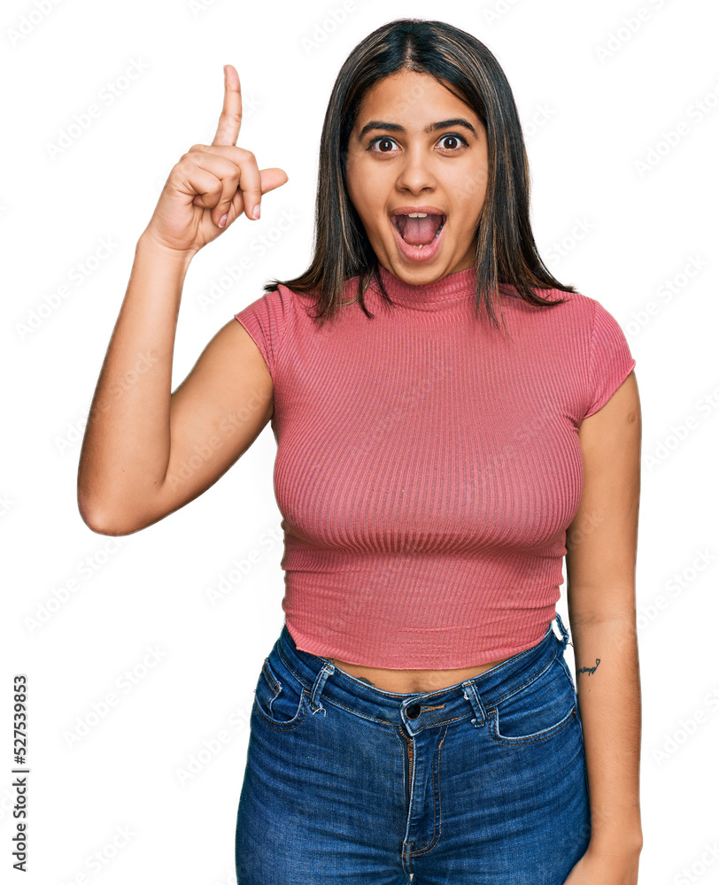 Young hispanic girl wearing casual t shirt pointing finger up with successful idea. exited and happy. number one. Young hispanic girl wearing casual t shirt pointing finger up with successful idea. exited and happy. number one.