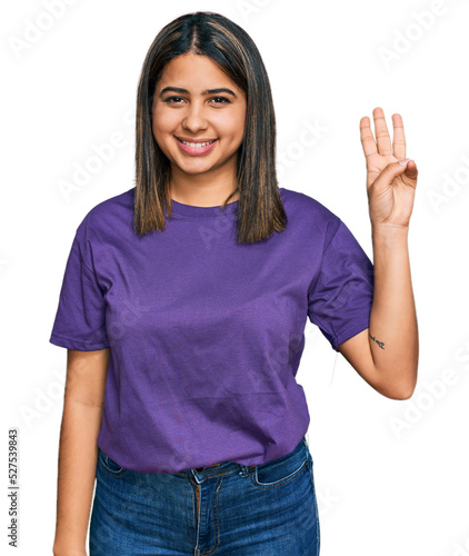 Young hispanic girl wearing casual purple t shirt showing and pointing up with fingers number three while smiling confident and happy.