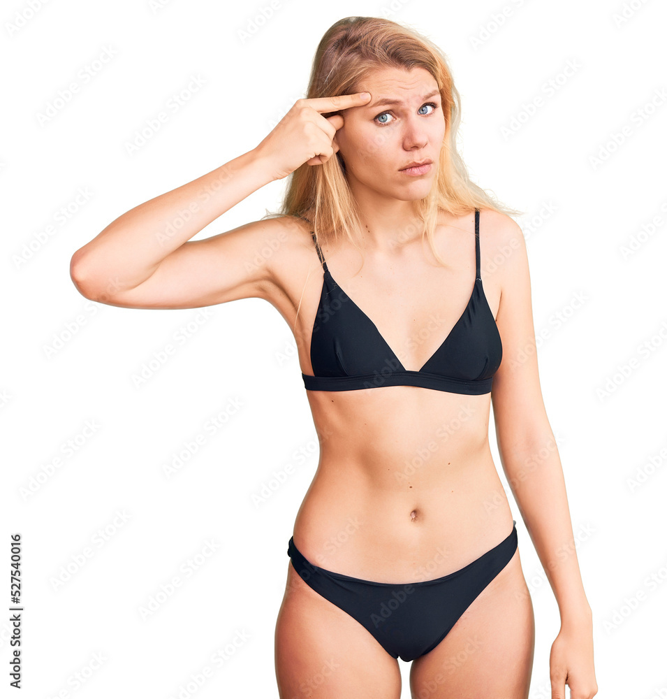 Young beautiful blonde woman wearing bikini pointing unhappy to pimple on forehead, ugly infection of blackhead. acne and skin problem Young beautiful blonde woman wearing bikini pointing unhappy to pimple on forehead, ugly infection of blackhead. acne and skin problem