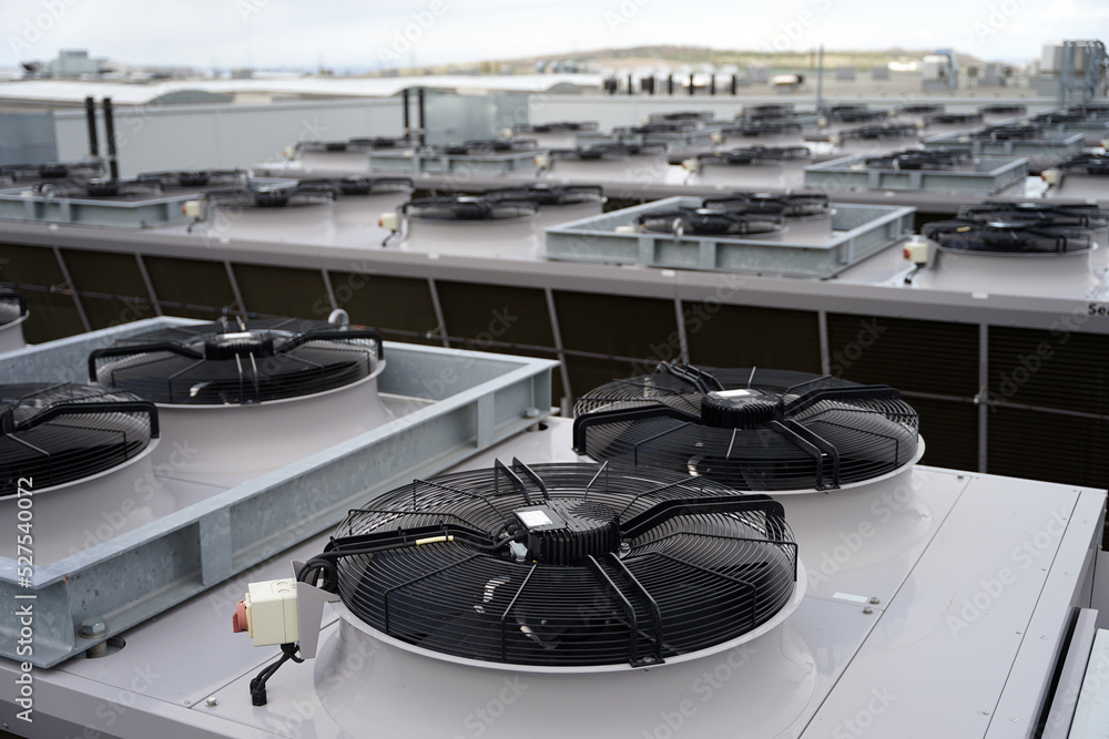 Large row of industrial condensers with fans on roof used in air conditioning, refrigeration, heat pump systems, green energy future concept