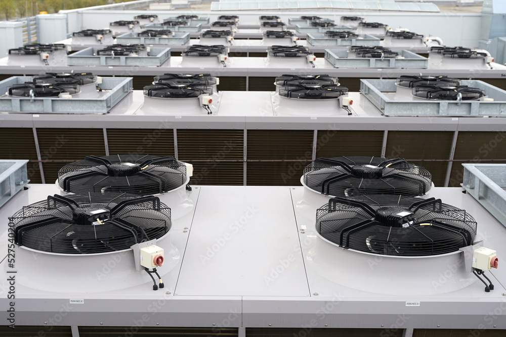Large row of industrial condensers with fans on roof used in air conditioning, refrigeration, heat pump systems, renewable green energy future concept