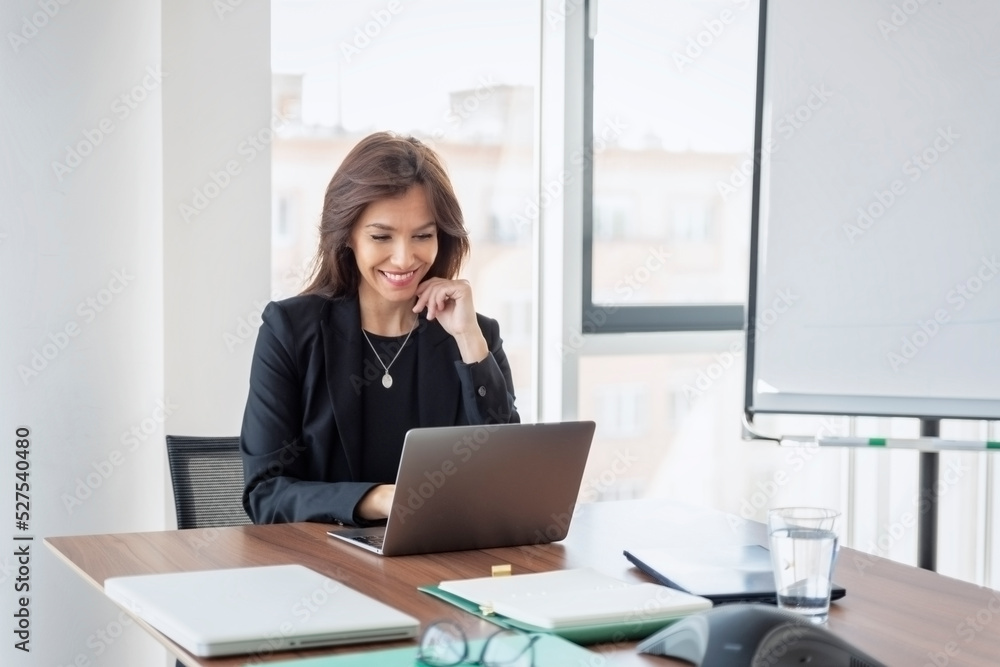 Attractive businesswoman having video call while sitting at office desk Attractive businesswoman having video call while sitting at office desk