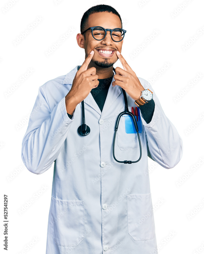 Young african american man wearing doctor uniform and stethoscope smiling with open mouth, fingers pointing and forcing cheerful smile Young african american man wearing doctor uniform and stethoscope smiling with open mouth, fingers pointing and forcing cheerful smile