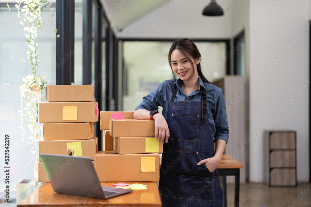 Fototapeta premium Portrait of Asian young woman SME working with a box at home the workplace.start-up small business owner, small business entrepreneur SME or freelance business online and delivery concept.