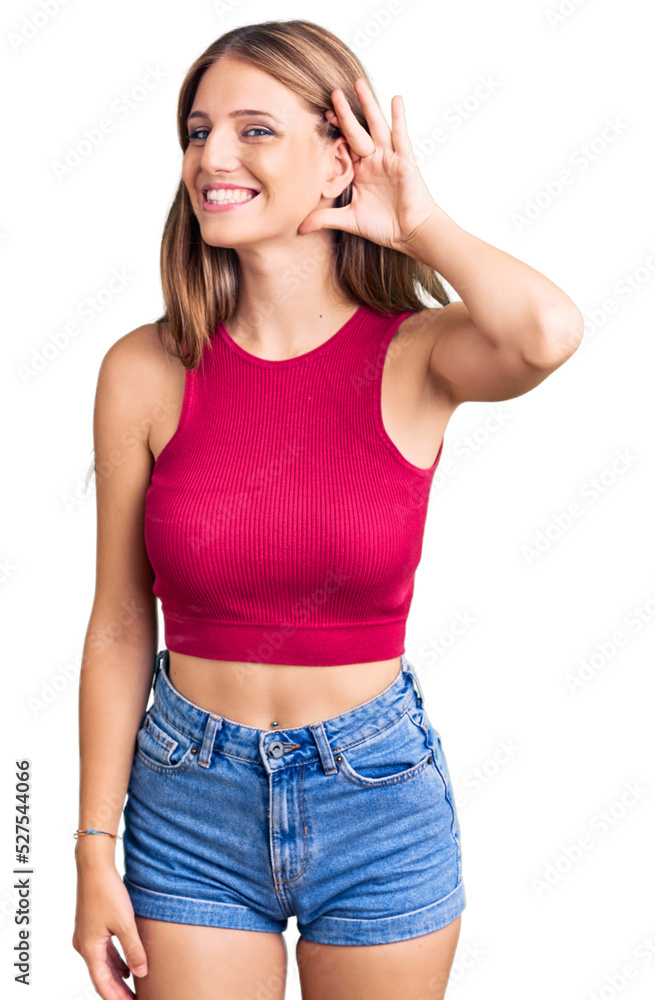 Young beautiful blonde woman wearing elegant summer shirt smiling with hand over ear listening an hearing to rumor or gossip. deafness concept. Young beautiful blonde woman wearing elegant summer shirt smiling with hand over ear listening an hearing to rumor or gossip. deafness concept.