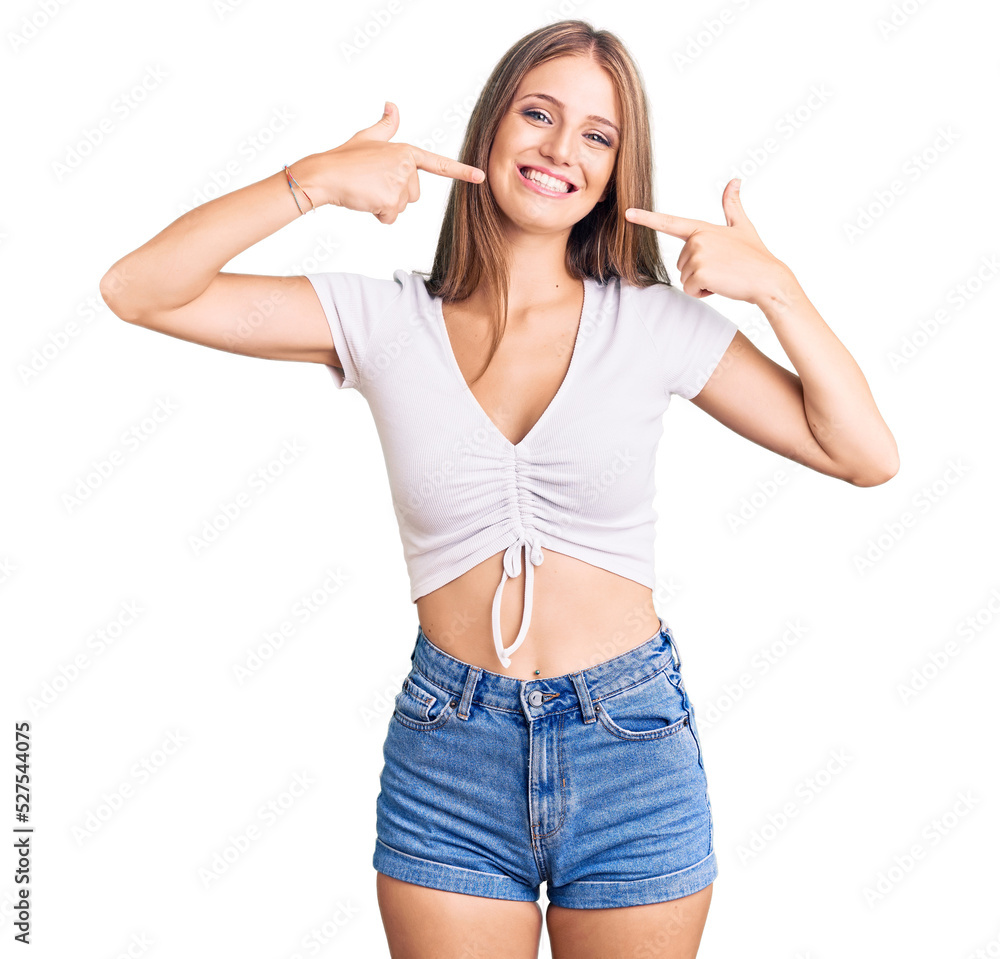 Young beautiful blonde woman wearing casual white tshirt smiling cheerful showing and pointing with fingers teeth and mouth. dental health concept. Young beautiful blonde woman wearing casual white tshirt smiling cheerful showing and pointing with fingers teeth and mouth. dental health concept.