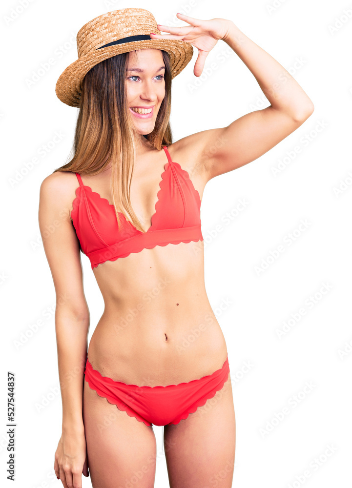 Beautiful brunette young woman wearing bikini very happy and smiling looking far away with hand over head. searching concept. Beautiful brunette young woman wearing bikini very happy and smiling looking far away with hand over head. searching concept.