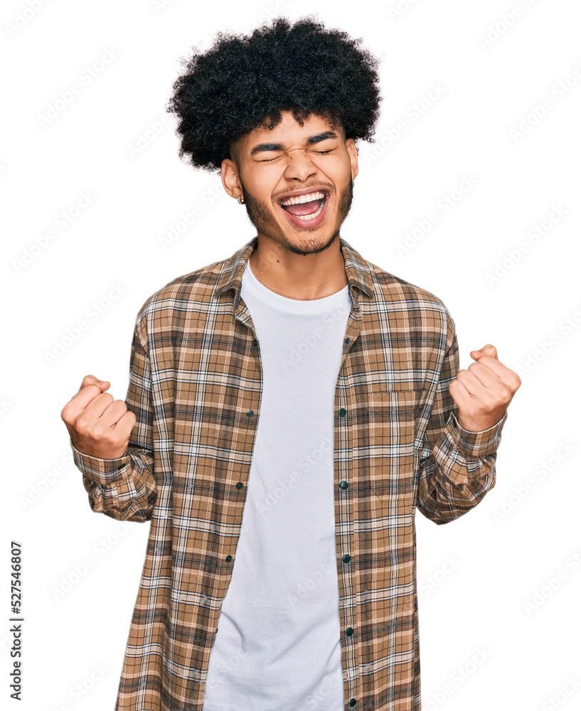 Young african american man with afro hair wearing casual clothes excited for success with arms raised and eyes closed celebrating victory smiling. winner concept. Young african american man with afro hair wearing casual clothes excited for success with arms raised and eyes closed celebrating victory smiling. winner concept.