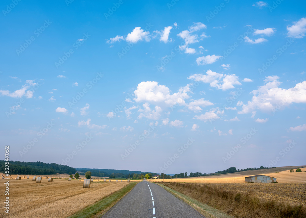 lorraine landscape with road in the north of france with straw bales under blue summer sky
