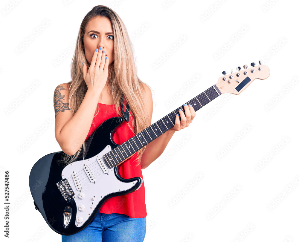 Young beautiful blonde woman playing electric guitar covering mouth with hand, shocked and afraid for mistake. surprised expression Young beautiful blonde woman playing electric guitar covering mouth with hand, shocked and afraid for mistake. surprised expression