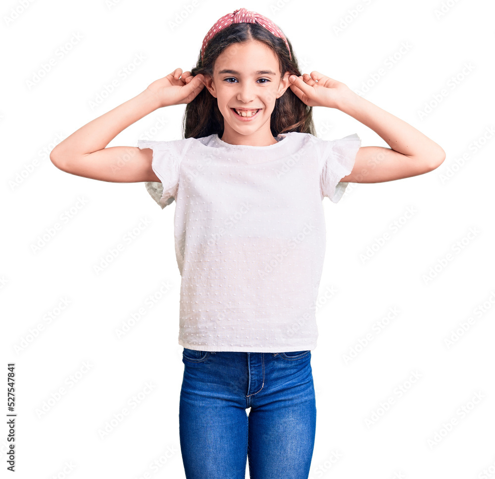 Cute hispanic child girl wearing casual white tshirt smiling pulling ears with fingers, funny gesture. audition problem Cute hispanic child girl wearing casual white tshirt smiling pulling ears with fingers, funny gesture. audition problem