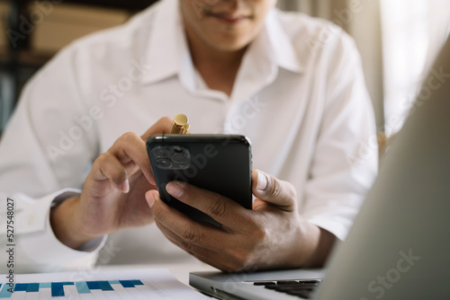 Male businessman working with smart phone and laptop in the morning.