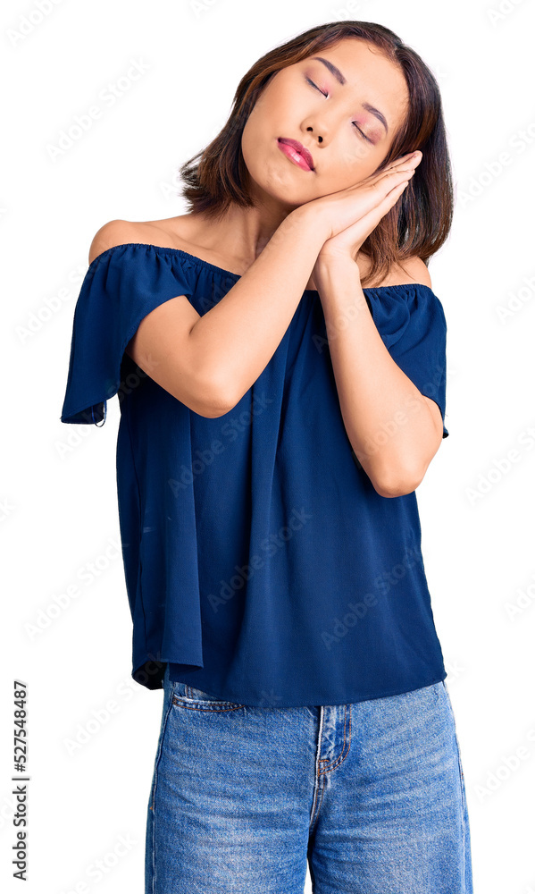 Young beautiful chinese girl wearing casual clothes sleeping tired dreaming and posing with hands together while smiling with closed eyes. Young beautiful chinese girl wearing casual clothes sleeping tired dreaming and posing with hands together while smiling with closed eyes.