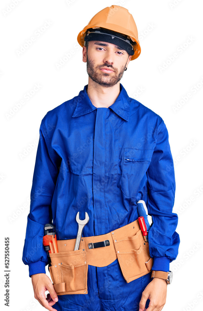 Young hispanic man wearing worker uniform relaxed with serious expression on face. simple and natural looking at the camera.