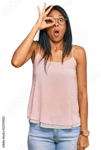 Young african american woman wearing casual clothes and glasses doing ok gesture shocked with surprised face, eye looking through fingers. unbelieving expression. © Krakenimages.com