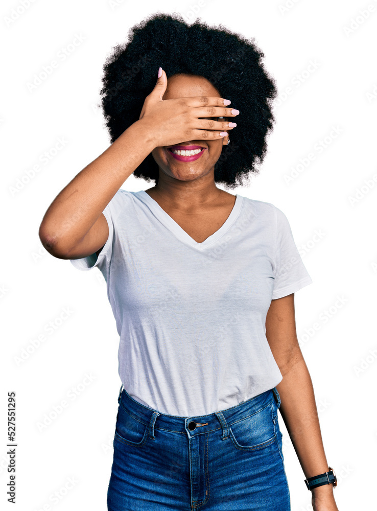 Young african american woman wearing casual white t shirt smiling and laughing with hand on face covering eyes for surprise. blind concept. Young african american woman wearing casual white t shirt smiling and laughing with hand on face covering eyes for surprise. blind concept.
