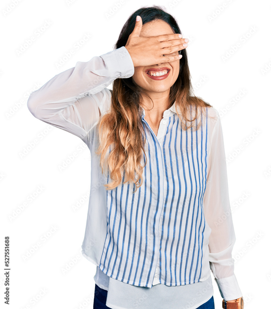 Beautiful hispanic woman wearing casual striped shirt smiling and laughing with hand on face covering eyes for surprise. blind concept. Beautiful hispanic woman wearing casual striped shirt smiling and laughing with hand on face covering eyes for surprise. blind concept.