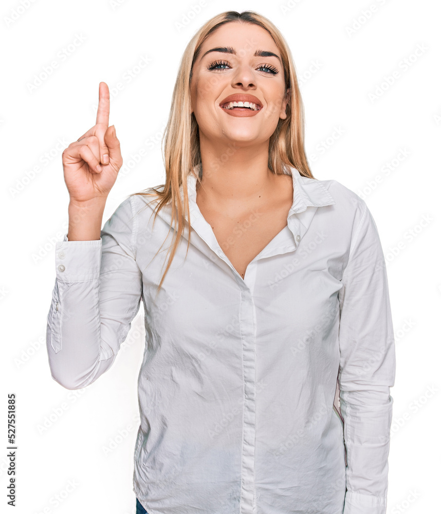 Young caucasian woman wearing casual clothes showing and pointing up with finger number one while smiling confident and happy. Young caucasian woman wearing casual clothes showing and pointing up with finger number one while smiling confident and happy.