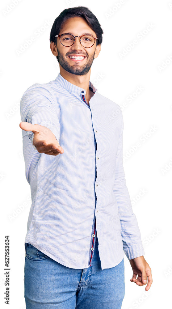 Handsome hispanic man wearing business shirt and glasses smiling cheerful offering palm hand giving assistance and acceptance. Handsome hispanic man wearing business shirt and glasses smiling cheerful offering palm hand giving assistance and acceptance.