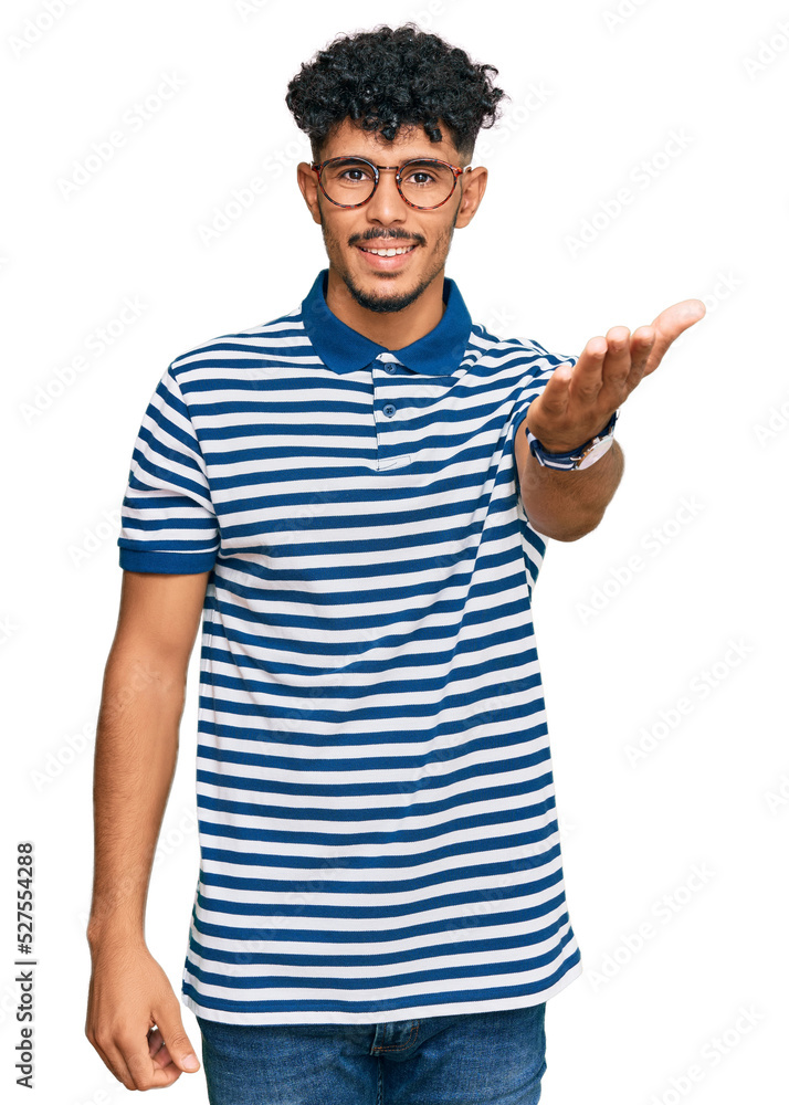 Young arab man wearing casual clothes and glasses smiling friendly offering handshake as greeting and welcoming. successful business. Young arab man wearing casual clothes and glasses smiling friendly offering handshake as greeting and welcoming. successful business.