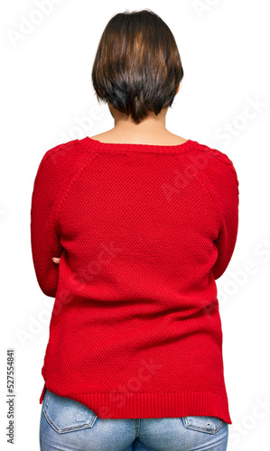 Young beautiful hispanic woman with short hair wearing casual sweater and glasses standing backwards looking away with crossed arms