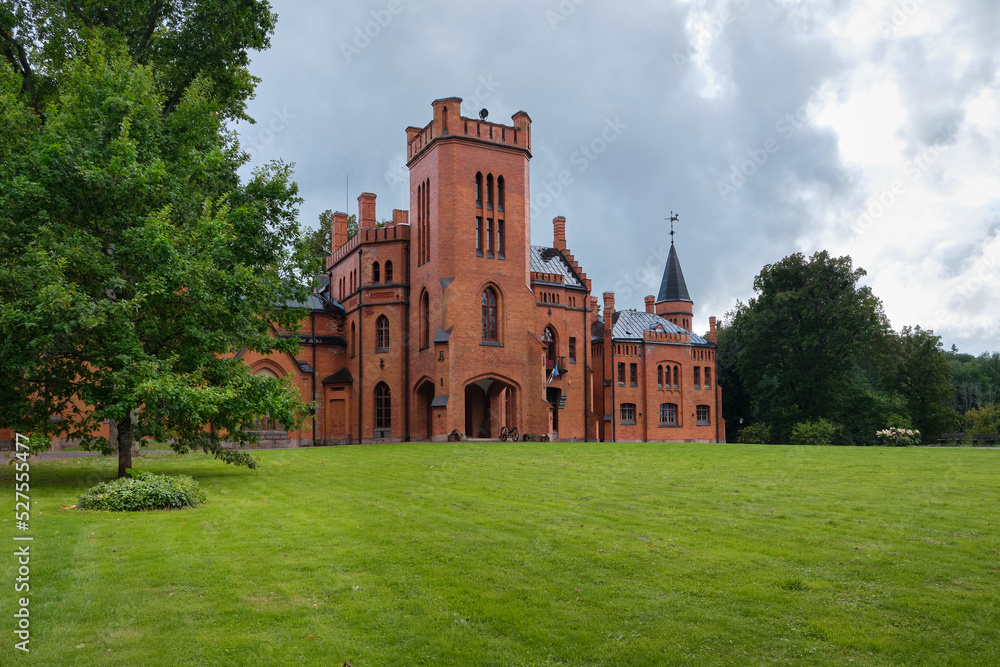 Estonia, Sangaste Castle, built in Neo-Gothic style in n 1879-1883. Main castle building with green lawn in front on a gloomy day under grey sky.