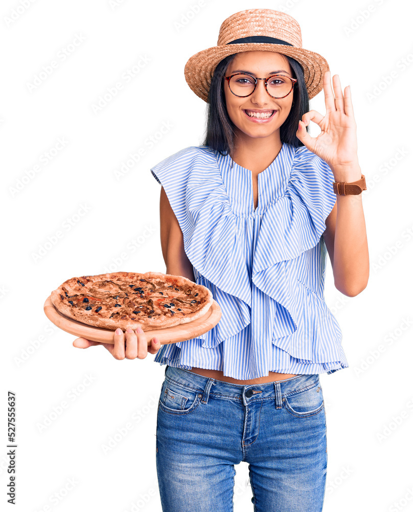 Young beautiful latin girl wearing summer hat and glasses holding pizza doing ok sign with fingers, smiling friendly gesturing excellent symbol Young beautiful latin girl wearing summer hat and glasses holding pizza doing ok sign with fingers, smiling friendly gesturing excellent symbol