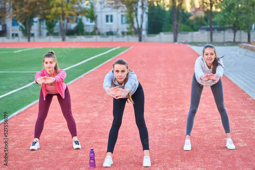 Three girls doing stretching exercises at the stadium