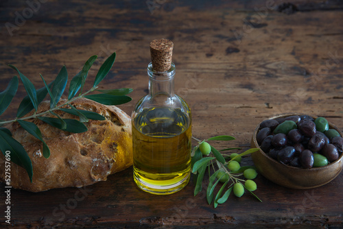 still life of olive oil, olive leaves and fruit with bread.