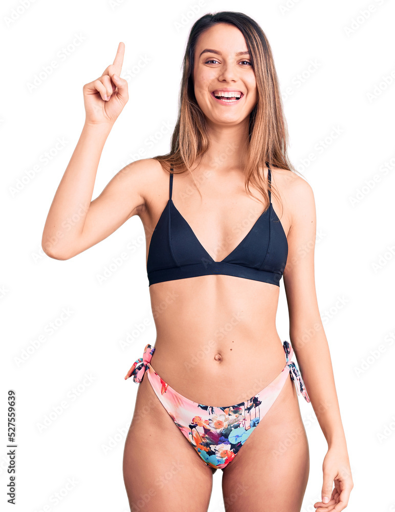Young beautiful girl wearing bikini pointing finger up with successful idea. exited and happy. number one. Young beautiful girl wearing bikini pointing finger up with successful idea. exited and happy. number one.