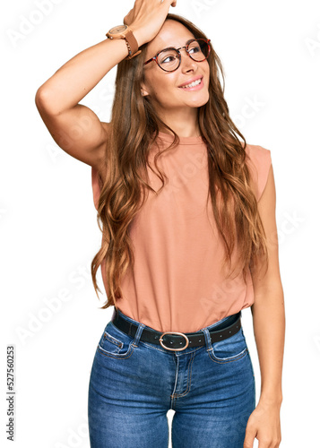 Young hispanic woman wearing casual clothes and glasses smiling confident touching hair with hand up gesture, posing attractive and fashionable