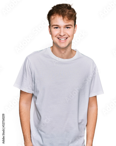 Young caucasian man wearing casual white t shirt with a happy and cool smile on face. lucky person.