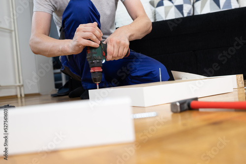 Wooden furniture assembling- woodworker screwing screws using a cordless.