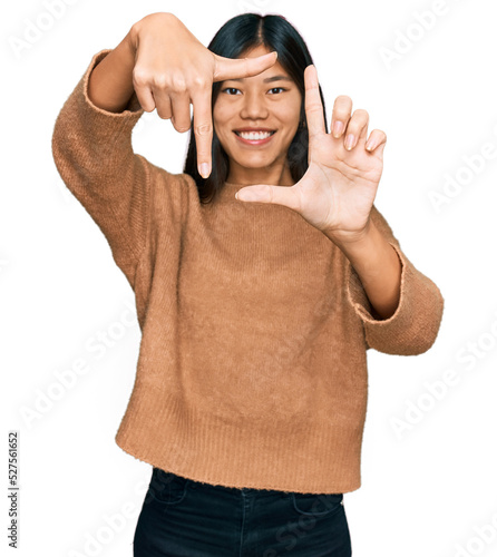 Beautiful young asian woman wearing casual winter sweater smiling making frame with hands and fingers with happy face. creativity and photography concept.
